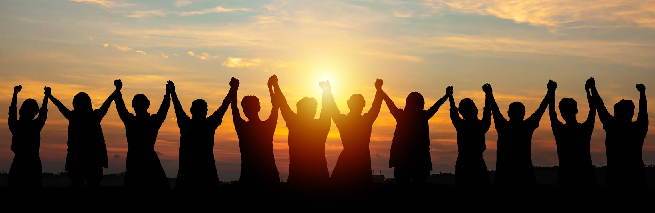 Silhouette of group business team making high hands over head in sunset sky
